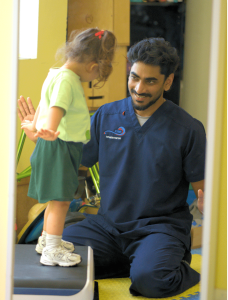 ABLE physiotherapist supporting a young child to stand and balance