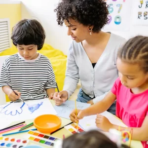 Early years practitioner observing children as they paint and draw