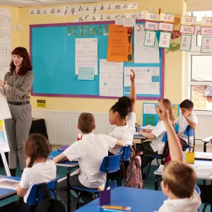 Primary school classroom with pupils raising their hands